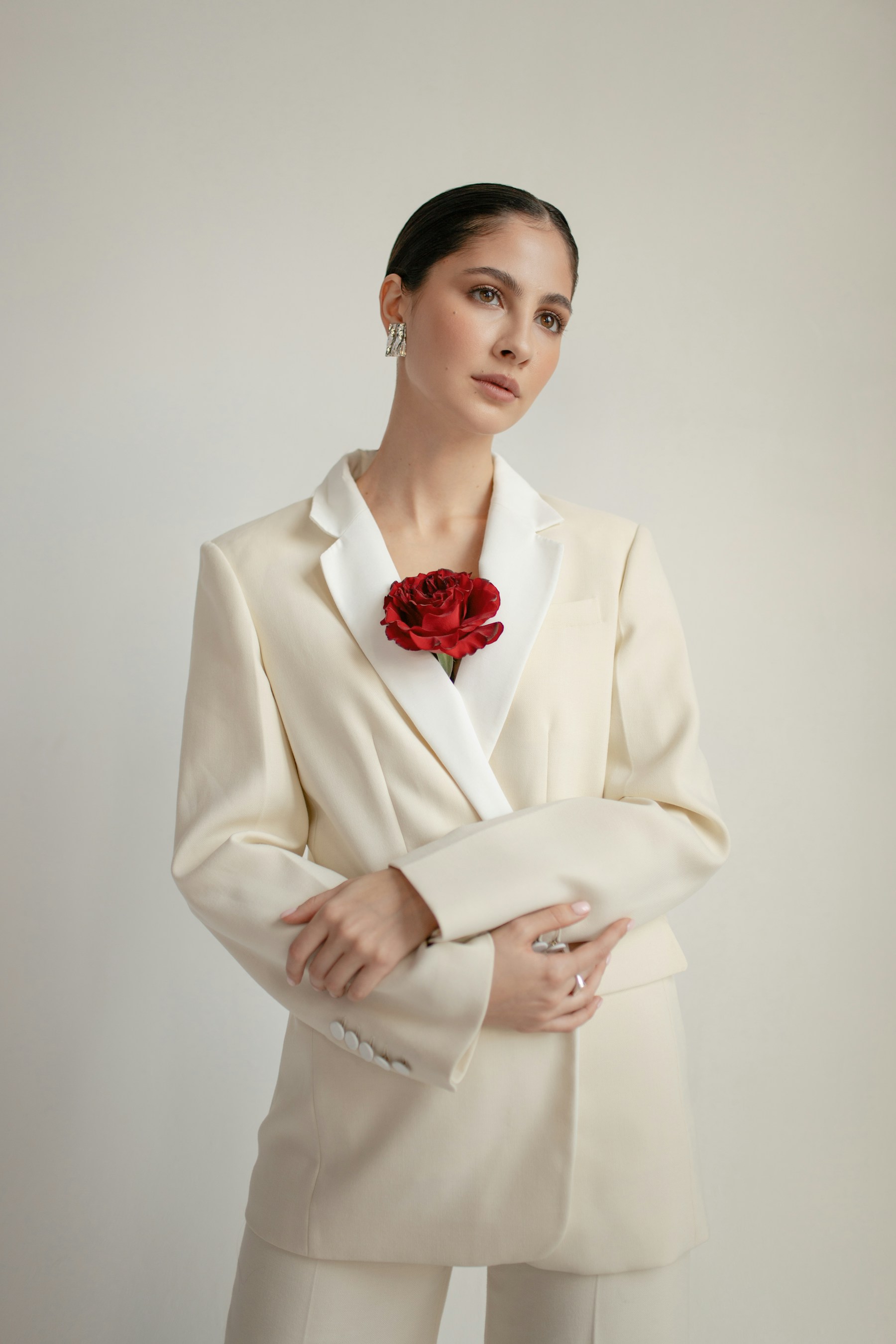 Editorial portrait of a woman in a cream suit with a red flower