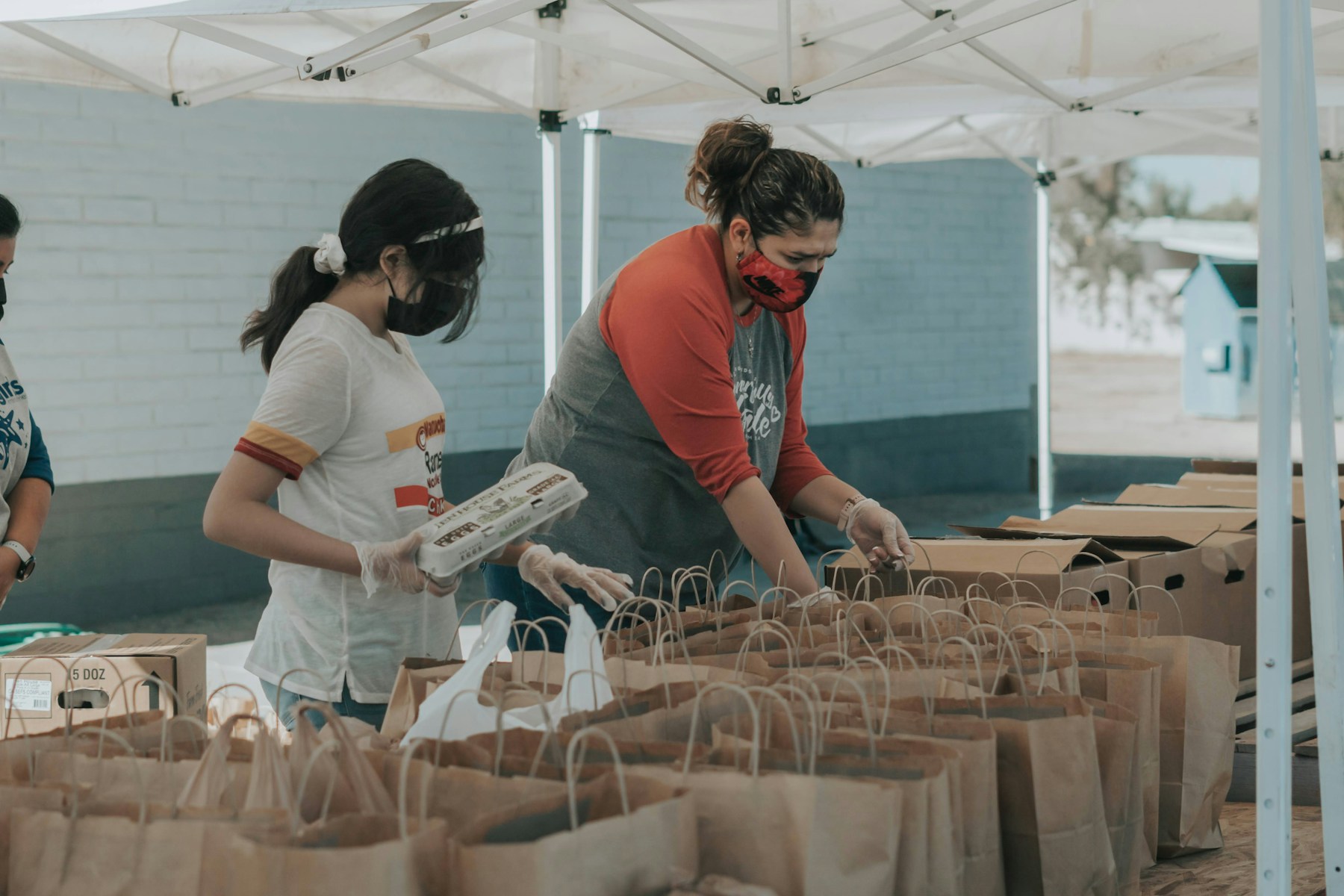 Volunteers packing paper bags with supplies outdoors